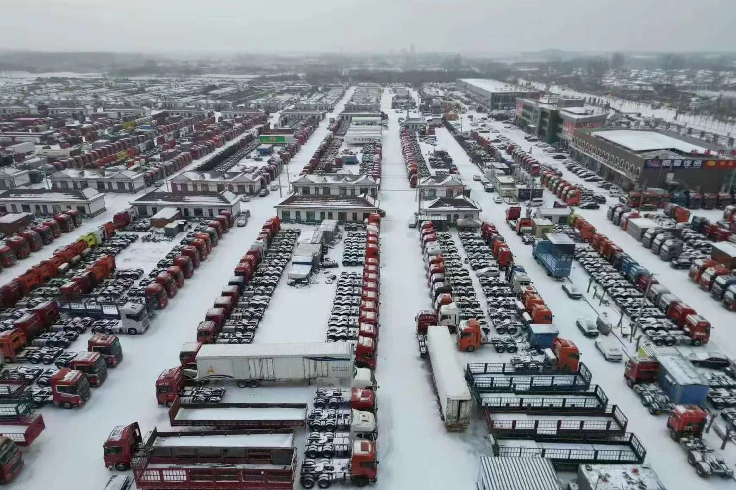 Aerial view of a used truck yard in Liangshan, Shandong, with rows of tractor heads and trailers