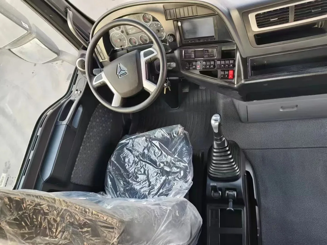 Interior of a used HOWO truck cab, showing steering wheel, dashboard and manual gear lever